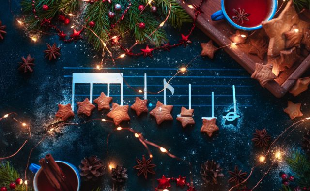 Christmas melody notes flat lay with star-shaped cookies, fir tree branches, wooden tray, anise