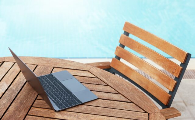 Laptop on table near swimming pool